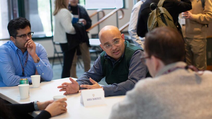 Image of Arkarup Banerjee speaking with graduate students at the 2025 CSHL Innovators Symposium