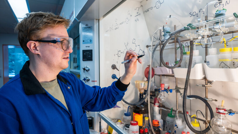 Image of Elliot Smith sketching a formula in the Moses lab