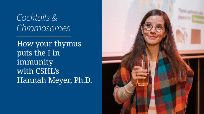 Hannah Meyer in glasses and plaid shawl holding a drink, standing by an event sign for a science talk.
